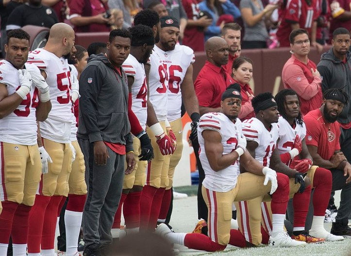 800px-San_Francisco_49ers_National_Anthem_Kneeling_(37721041581)